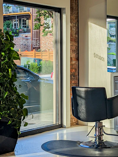 A bright, airy salon interior with sleek styling stations and natural light flooding in through large windows overlooking the bay.