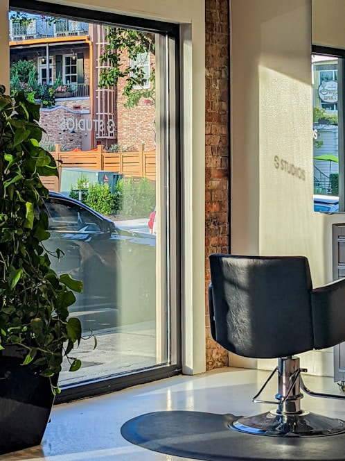A soft-pastel themed salon interior with rose-gold accents and a welcoming styling chair bathed in natural light