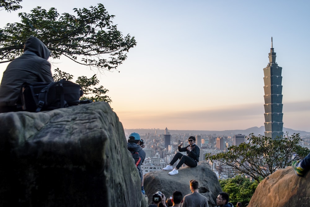 a group of people sitting on a rock overlooking a city