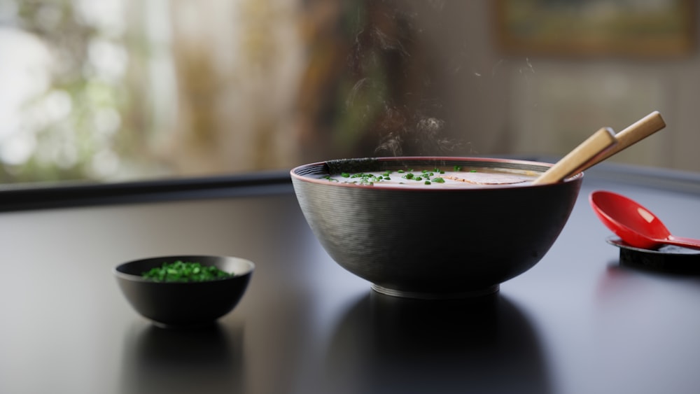 uma tigela de sopa com pauzinhos em uma mesa