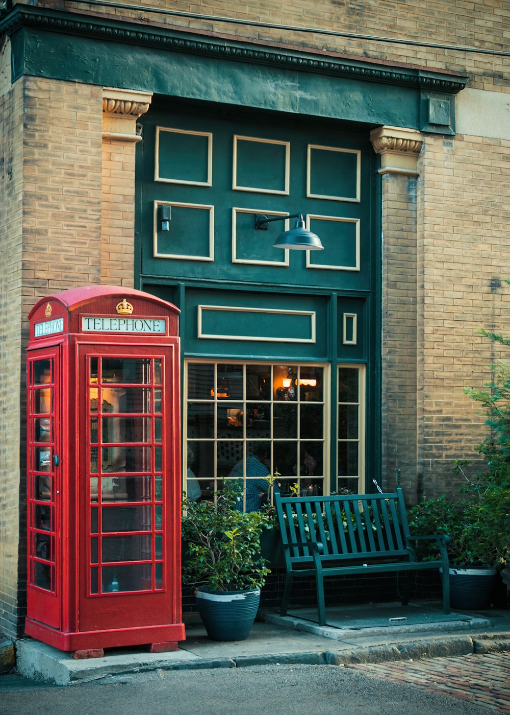 a red telephone booth next to a bench