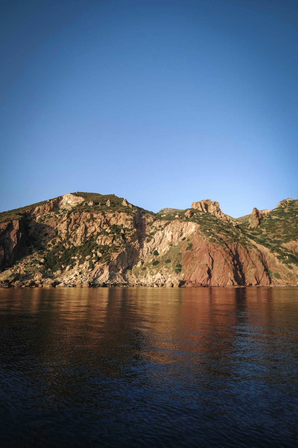 a rocky cliff next to a body of water