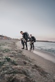 Group of divers preparing their gear on a sunny beach with volcanic landscape.