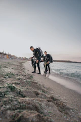A group of diverse scuba divers preparing their gear by the water on a sunny day.