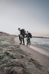 An instructor teaching a young diver how to use scuba gear on a sandy beach.