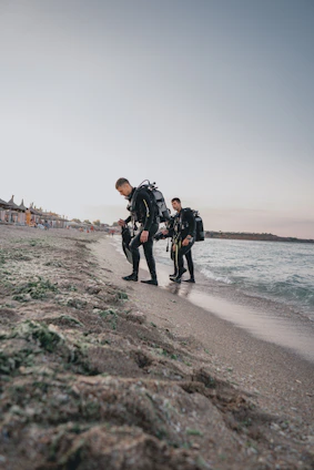 A group of diverse scuba divers preparing their gear by the water on a sunny day.