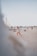 A group of friends playing beach volleyball under a clear blue sky.