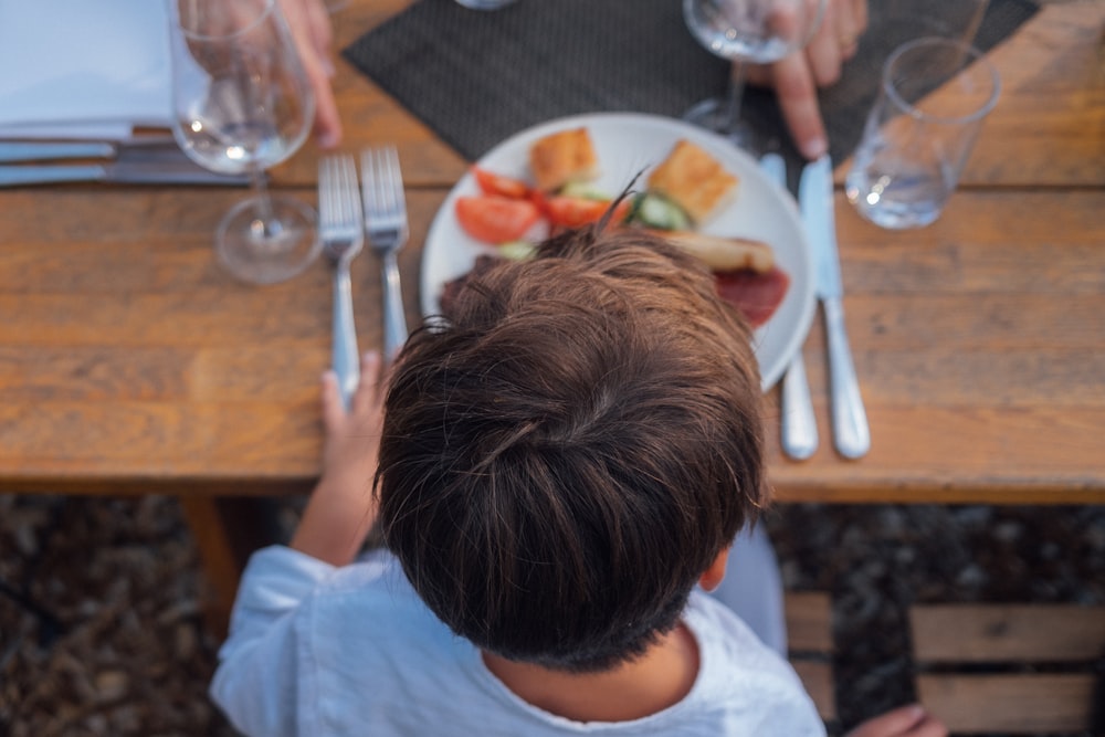 Eine Person, die an einem Tisch sitzt und Essen darauf hat