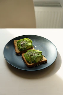 Delicious homemade avocado toast topped with seeds and microgreens on a ceramic plate