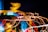 A dynamic, abstract composition featuring vivid streaks of red, yellow, and blue light against a dark background, creating a sense of motion and energy. The lights appear to be in the form of streaks or trails, possibly captured using long exposure photography.