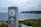 A signpost with the emblem of the National Parks & Wildlife Service is displayed prominently. The background reveals a coastal landscape with cliffs and the ocean under a cloudy sky.