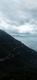A serene mountain road winding through misty hills under a clear sky.