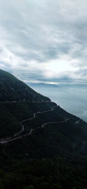 A serene mountain road winding through misty hills under a clear sky.