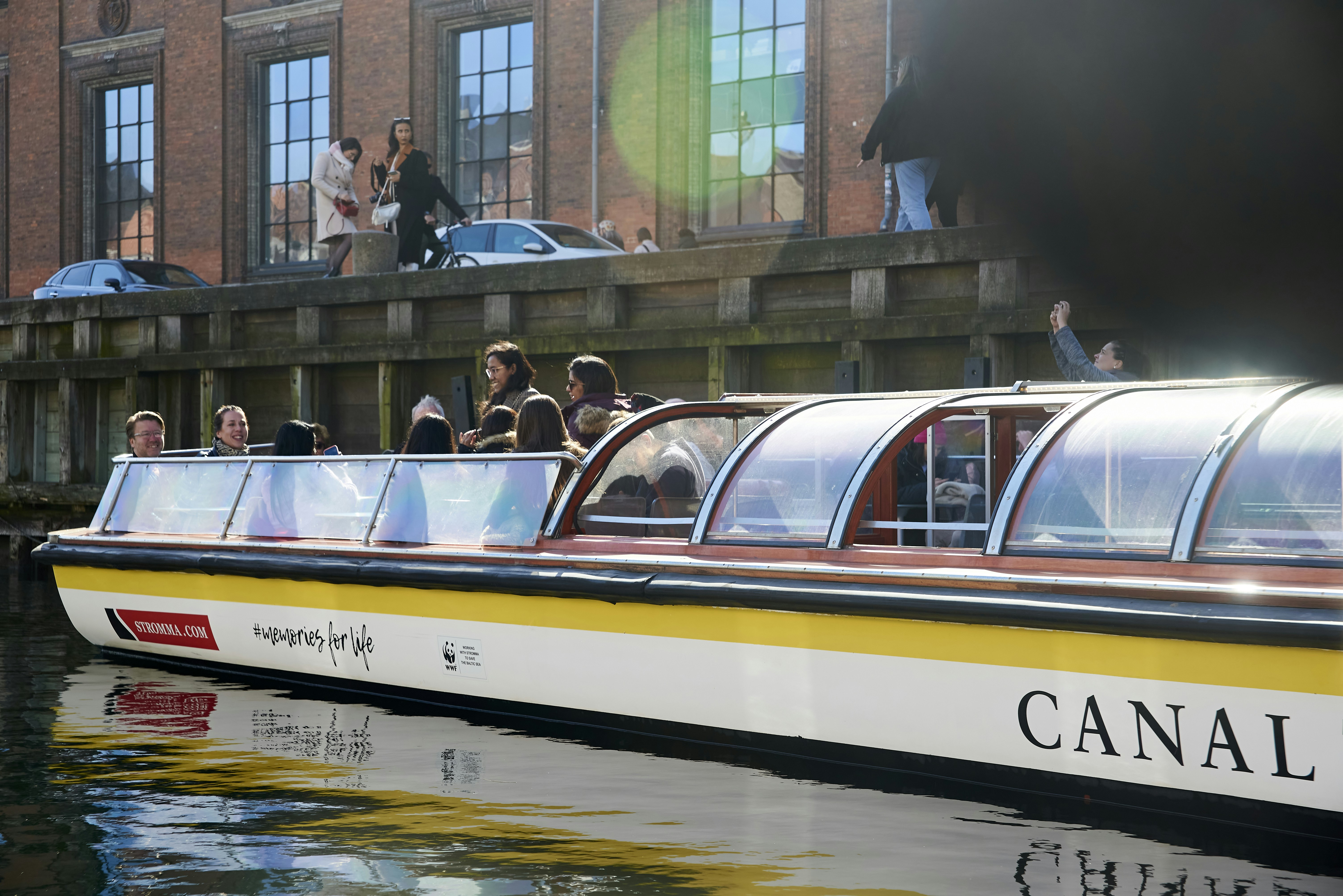 a boat with people on it, A sightseeing canal tour boat in Copenhagen