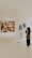 A person is standing in an art gallery, observing an exhibition. A large painting featuring several figures is displayed prominently on a white wall. Nearby, there are smaller black-and-white sketches. The gallery is well-lit, and the floor is polished.