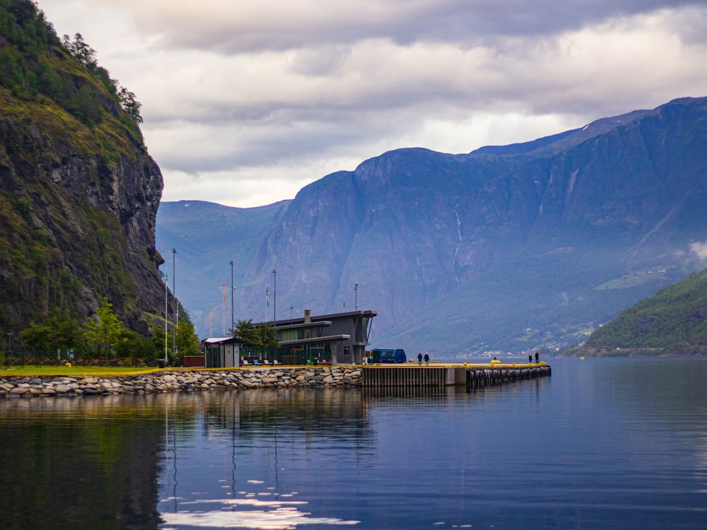 a building on a dock by a lake with mountains in the background