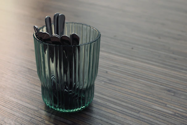 Rows of polished metal spoons reflecting soft workshop lighting.