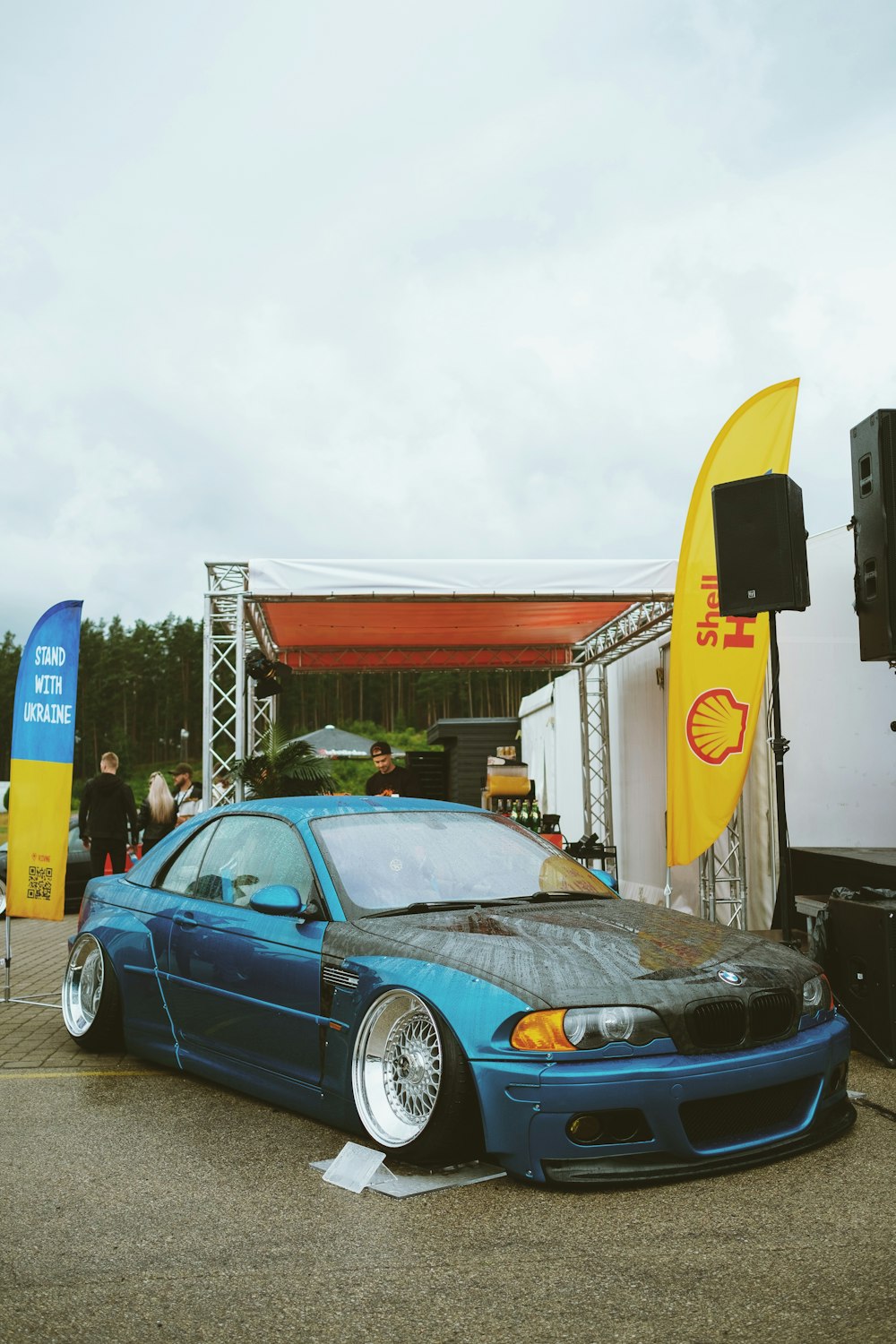 a blue car parked in front of a building with a yellow surfboard