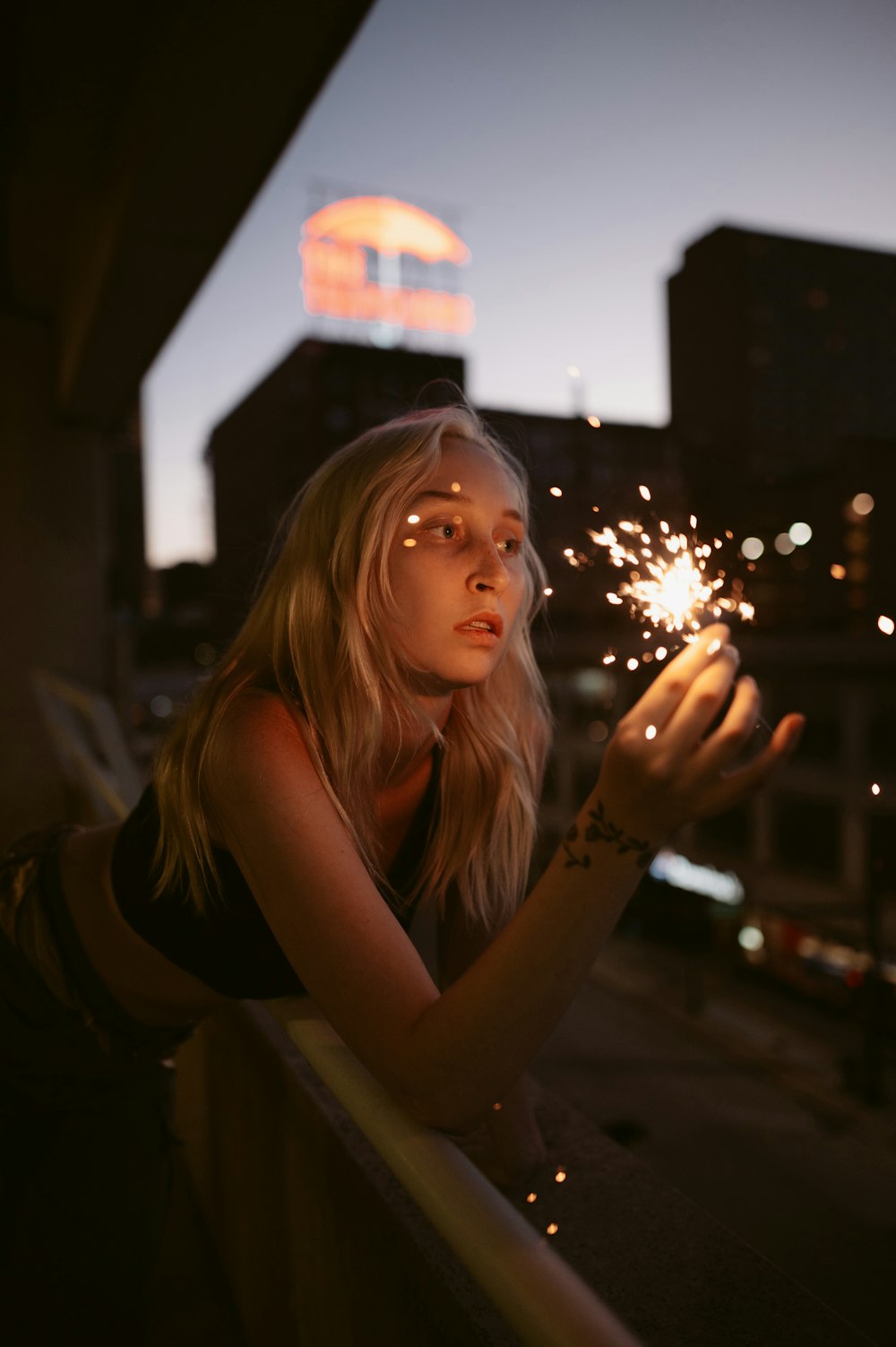 a woman sitting on a railing with a city skyline in the background