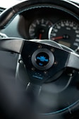 A close-up view of a car steering wheel, prominently featuring a brand logo labeled 'personal' in the center. The dashboard in the background shows the speedometer and other gauges.