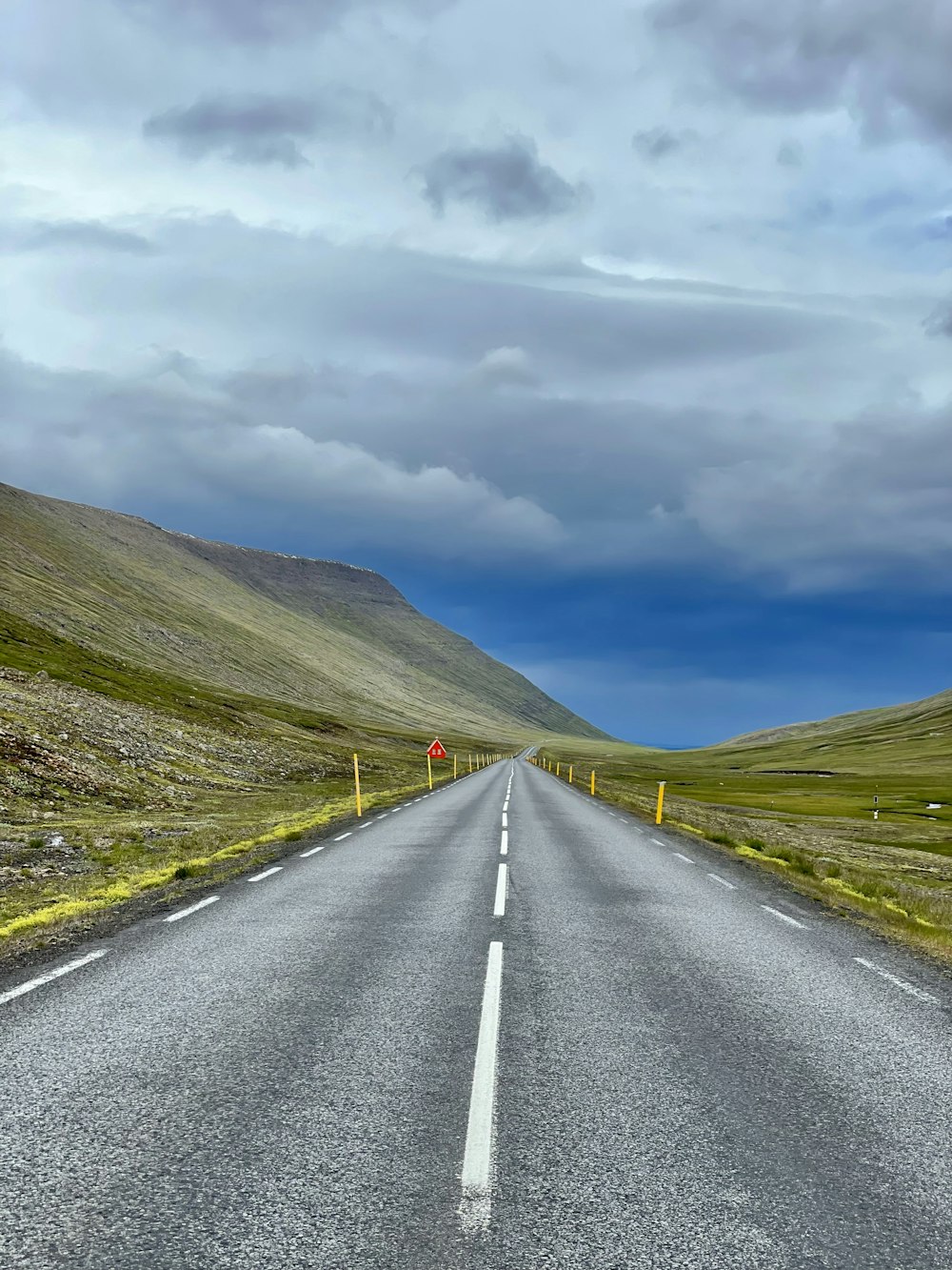 a road with grass and hills on either side of it