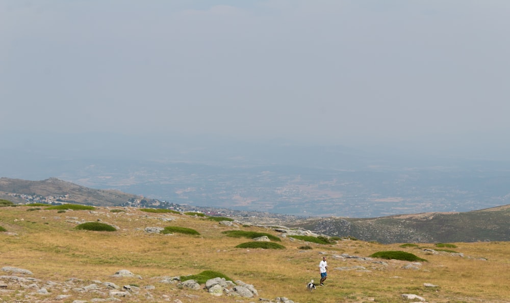 Eine Person, die mit einem Hund auf einem felsigen Hügel spazieren geht