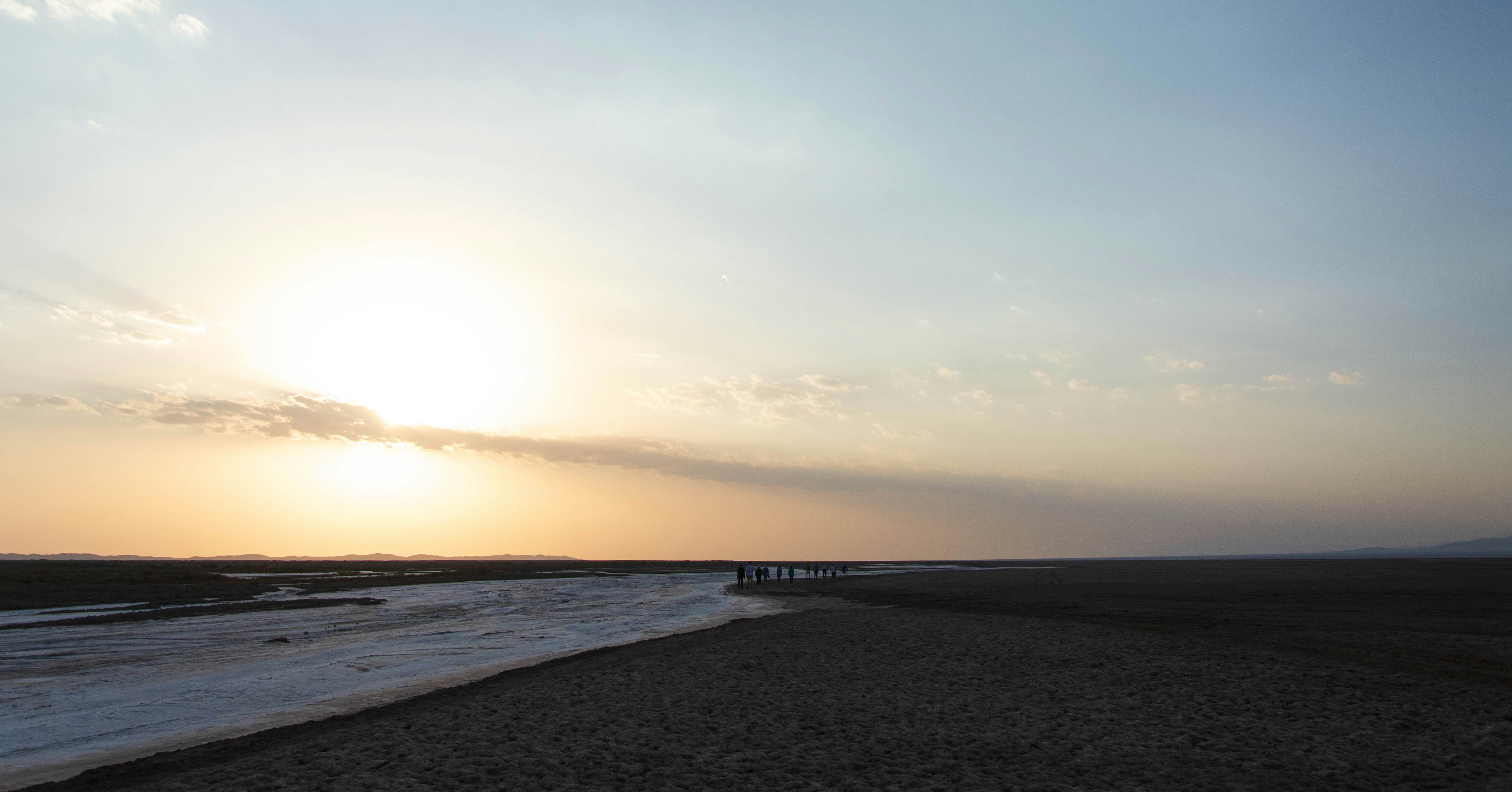 a beach with a body of water and a sunset