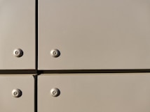 A close-up view of a section of a metal surface, featuring four screws with evenly spaced, flat panels. The panels are a light tan color with a slightly reflective finish, and they are arranged in a grid with visible seams.