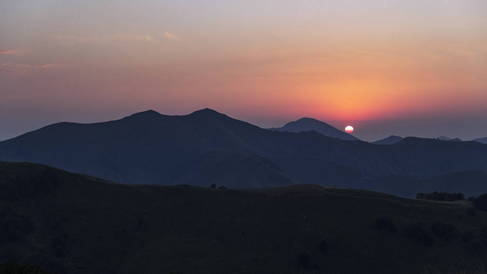 Un paisaje con colinas y una puesta de sol
