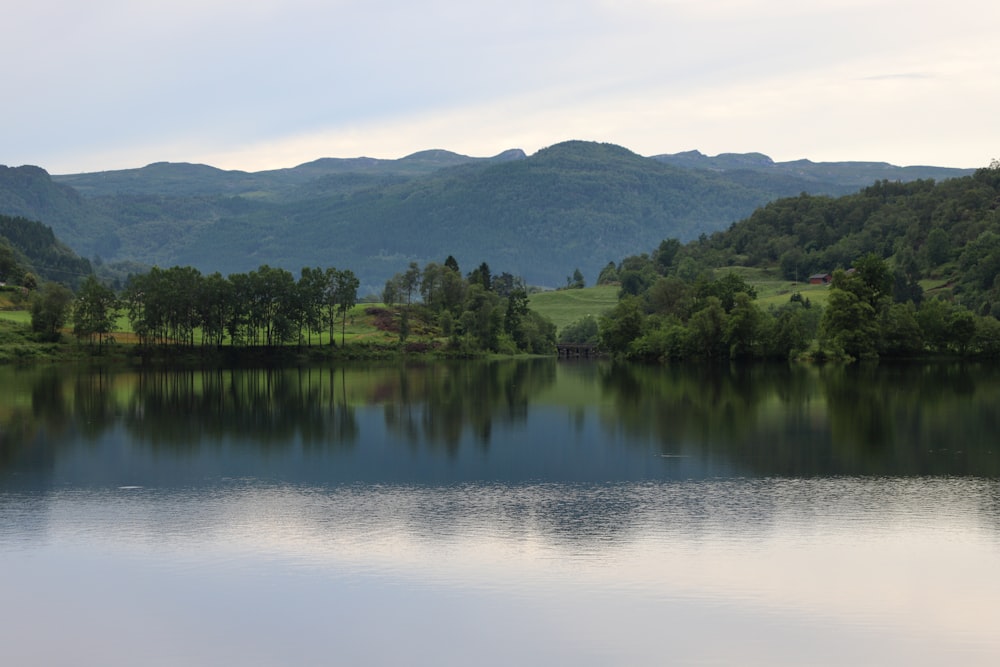 a lake with trees and hills in the background