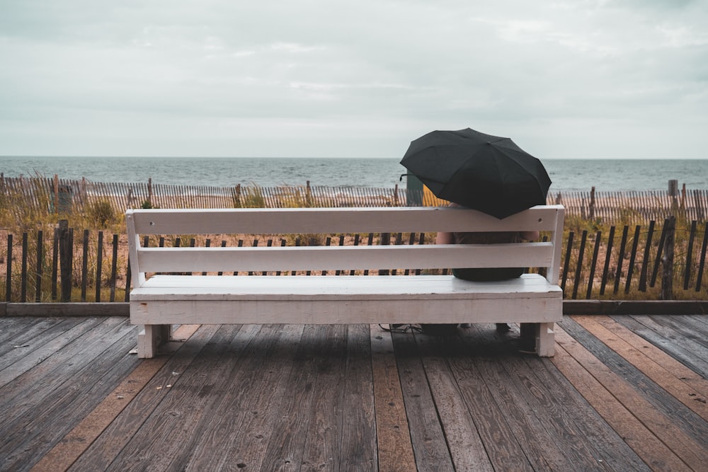 a person sitting on a bench with an umbrella