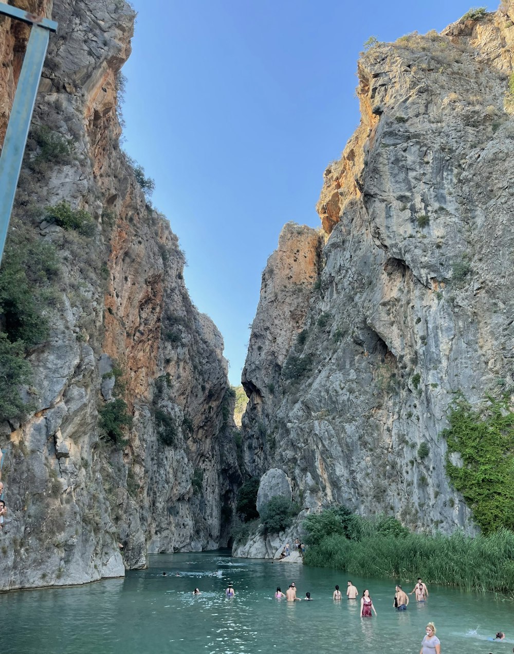 a group of people in a body of water by large rocks