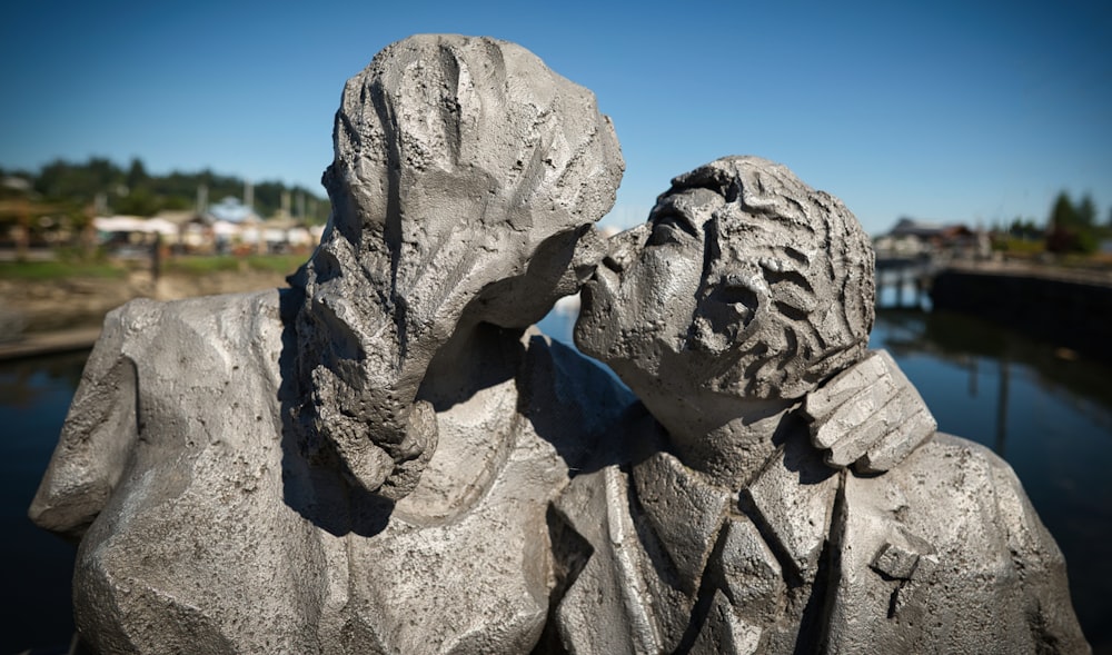 a statue of a person with a beard on a rock by water