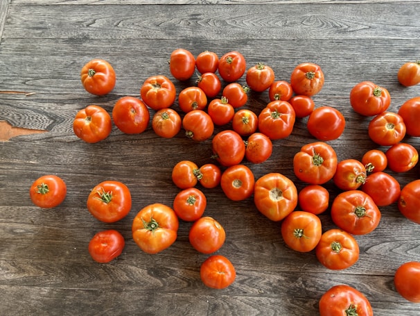 Bright red tomatoes glistening with morning dew on a rustic wooden table.