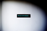 A black rectangular sign with turquoise text and a small symbol on a plain white wall. The text reads 'See you next page' with a small waving hand emoji at the end. The lighting creates a gradient shadow effect around the perimeter of the image.