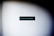 A black rectangular sign with turquoise text and a small symbol on a plain white wall. The text reads 'See you next page' with a small waving hand emoji at the end. The lighting creates a gradient shadow effect around the perimeter of the image.