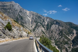a car driving on a road between mountains