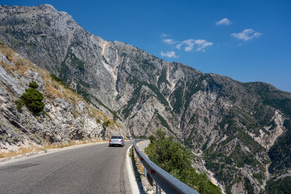 a car driving on a road between mountains