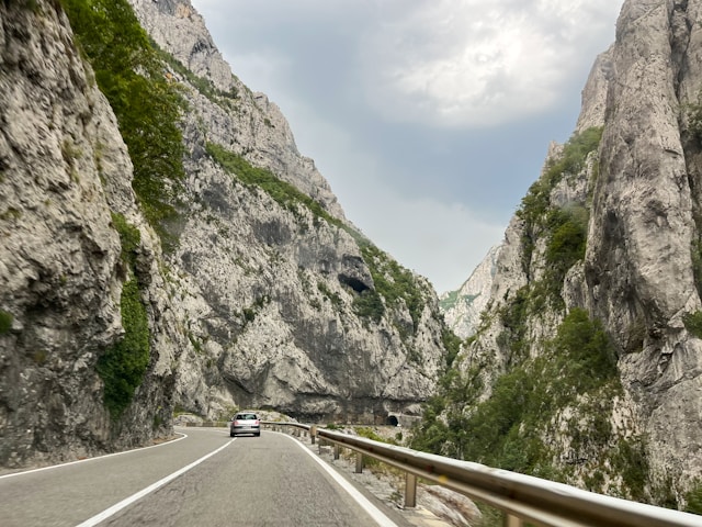 a car driving on a road between rocky cliffs