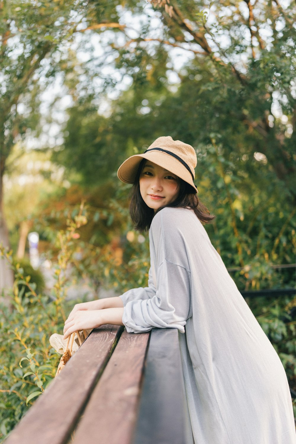 a person in a hat leaning on a wooden fence