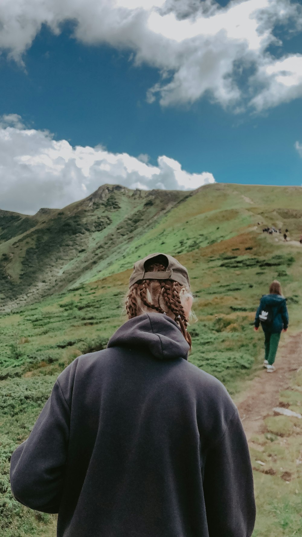 a person with a backpack walking on a dirt path in a hilly area