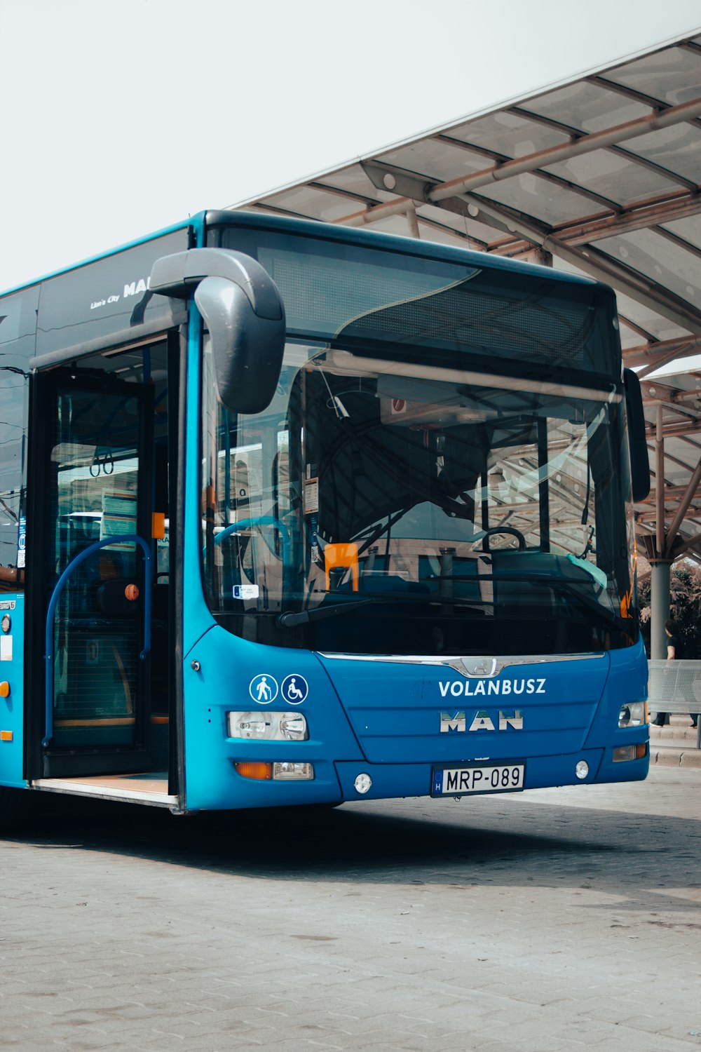a blue bus parked under a covered area