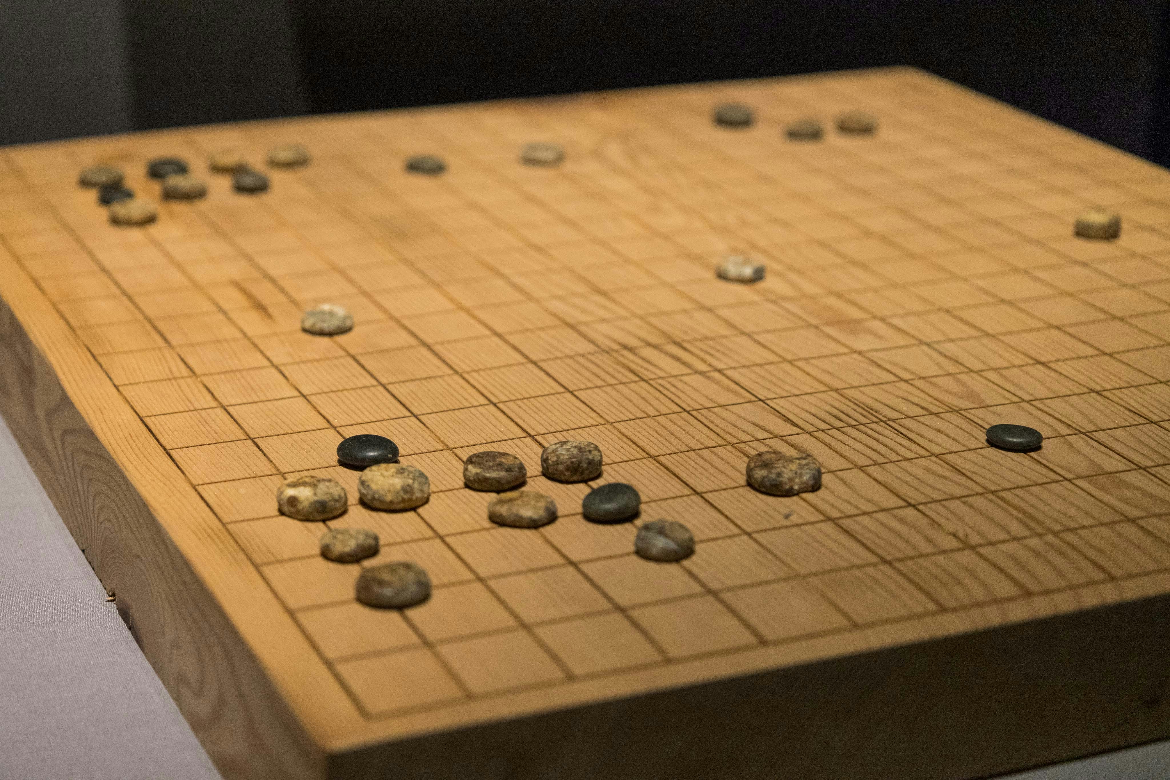Chess-like strategy board game pieces, ancient carved wooden tokens on stone surface