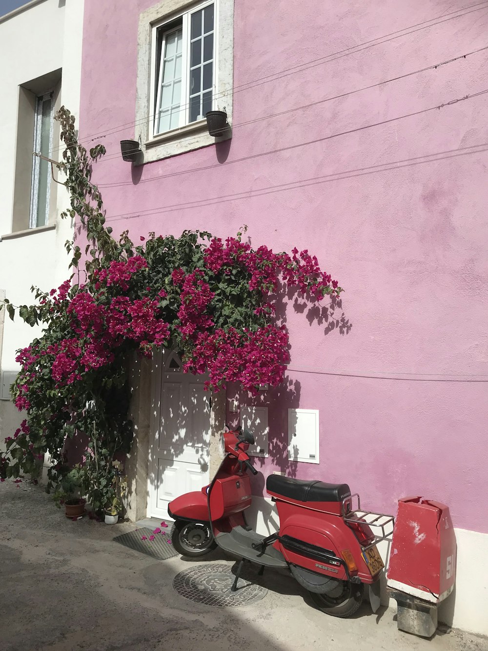 Un ciclomotor rosa estacionado junto a un edificio rosa
