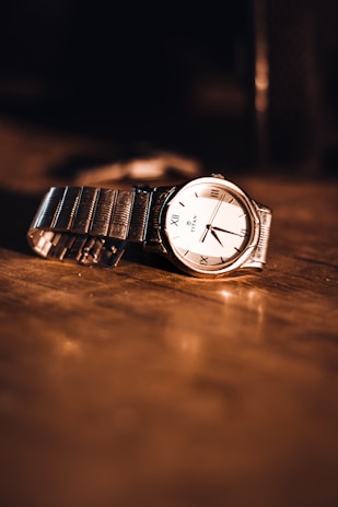 A close-up of a stylish wristwatch on a wooden surface.