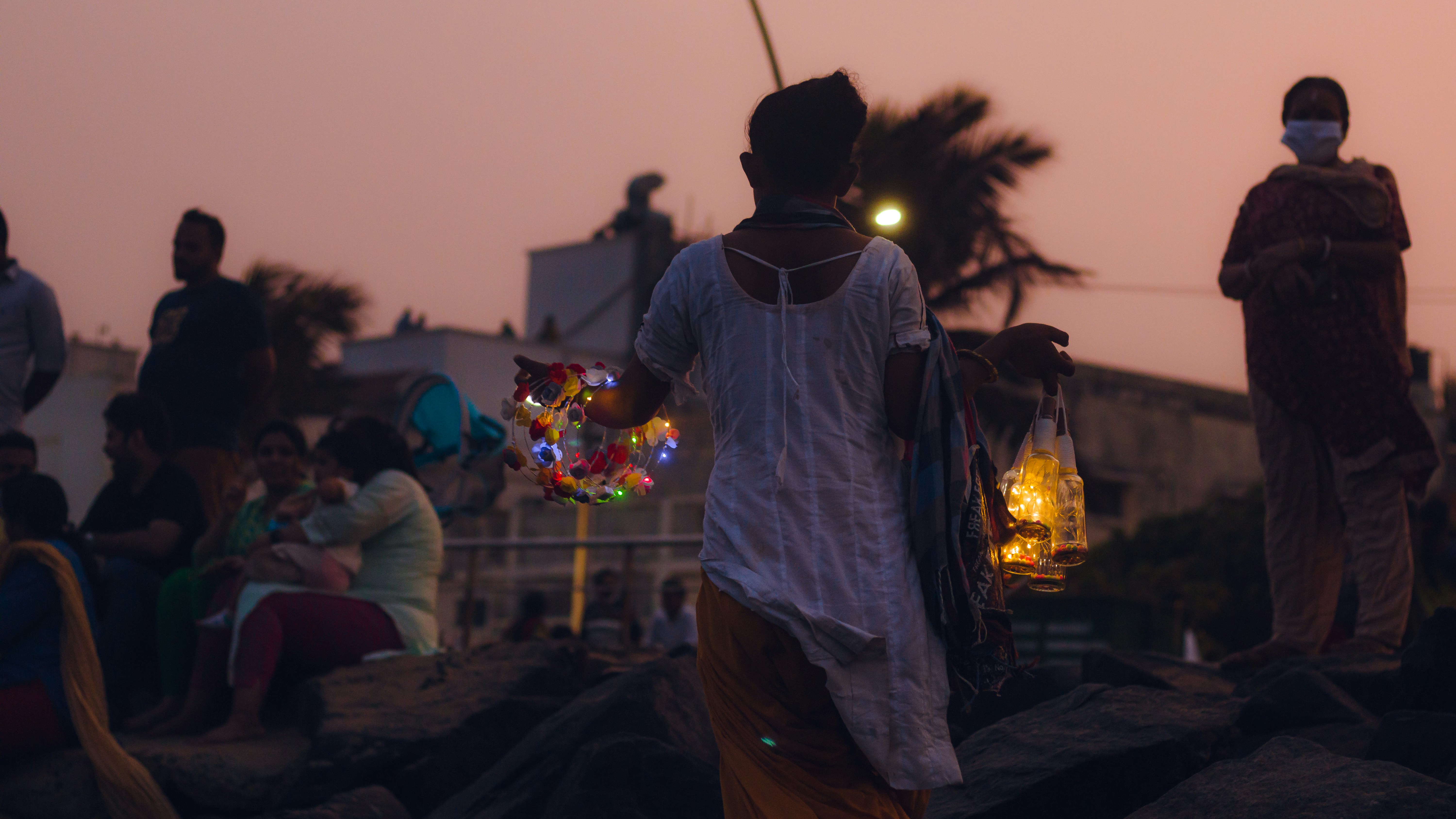 A tense night scene in a rural Indian village. Villagers are gathered with torches, looking fearful and angry. In the background, a small, dimly lit house with visible damage. Forest department vehicles can be seen in the distance.