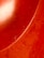 A close-up view of a red surface with noticeable scratches and scuff marks. The lighting creates a bright highlight on the smoother part of the surface, giving it a glossy appearance.