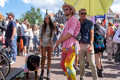 A lively pet fashion show with colorful costumes and excited spectators in the background.