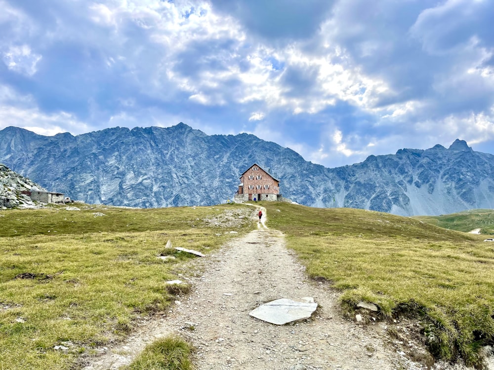 a person walking on a path in a grassy field with mountains in the background