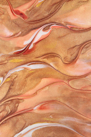 Soft gold particles drifting over a layered burnt gold and espresso brown gradient with subtle floral blurs.